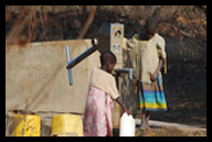Orphans gathering water at a borehole with a hand pump.